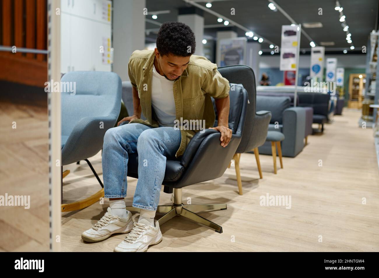Giovane uomo che sceglie sedia in negozio di mobili Foto Stock