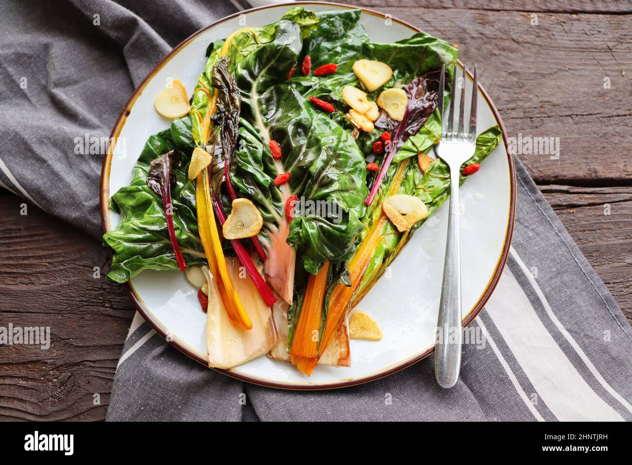 Insalata di bietole svizzera appassita con burro e aglio su tavola rustica. Foto Stock