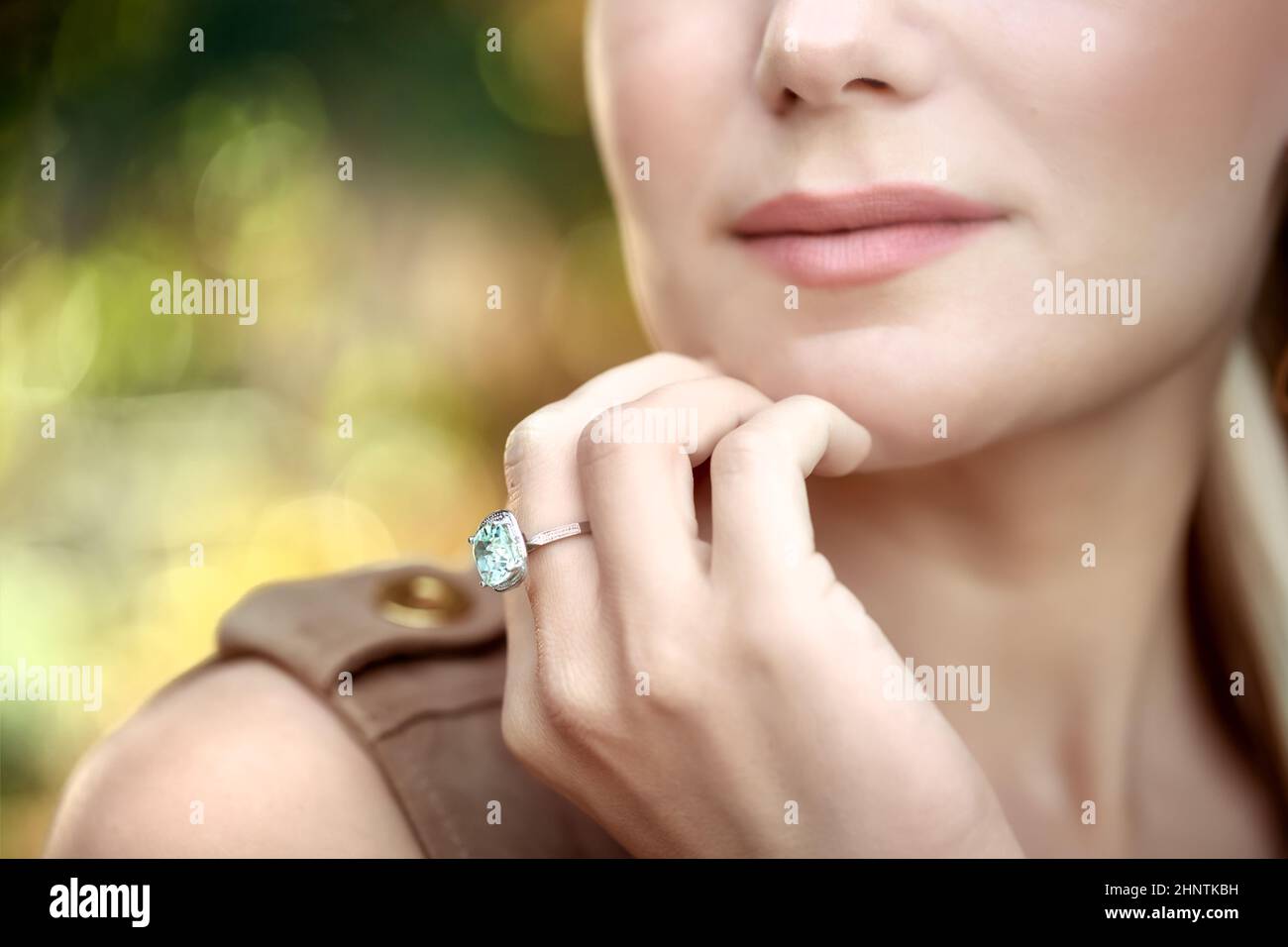 Primo piano Ritratto di una bella giovane donna che indossa splendido anello elegante con pietra preziosa Turquois. Parte di faccia. Gioielli alla moda di lusso. Foto Stock