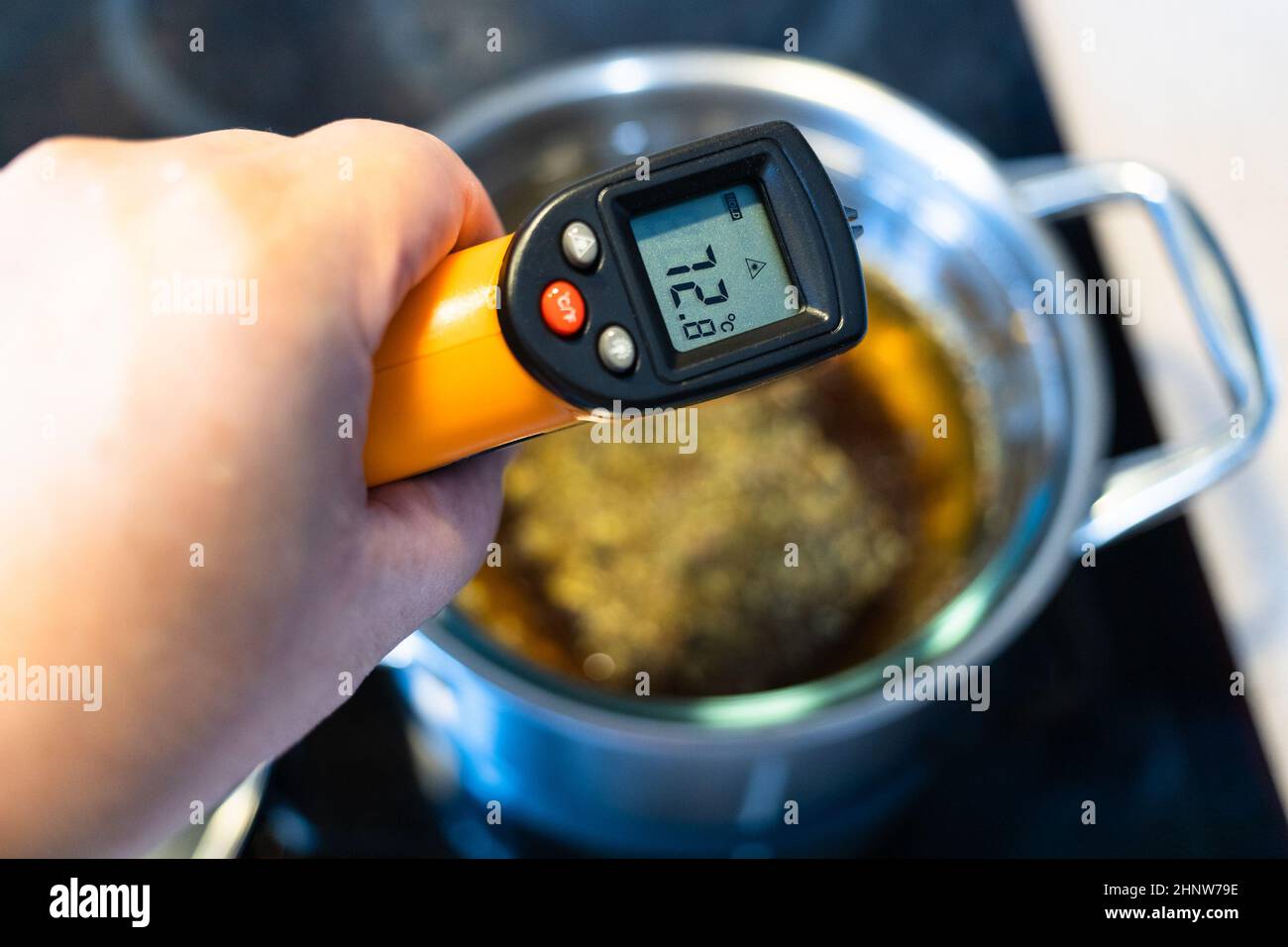 misurazione della temperatura di tintura di cottura da erbe medicinali in  bagno d'acqua con termometro a infrarossi su stufa in ceramica in cucina a  casa Foto stock - Alamy