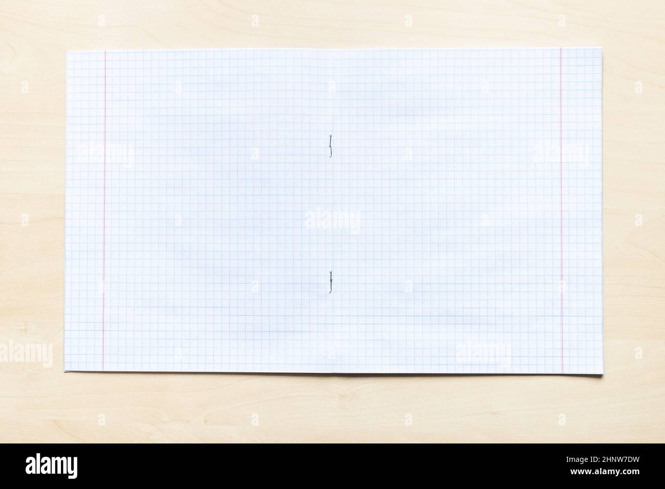 vista dall'alto di un quaderno vuoto aperto con fogli quadrati con margini su asse di legno marrone chiaro Foto Stock