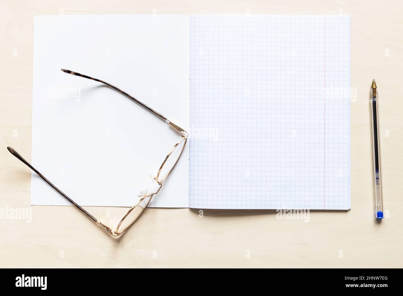 vista dall'alto della penna e degli occhiali su un quaderno vuoto aperto  della scuola con fogli quadrati con margini su asse di legno marrone chiaro  Foto stock - Alamy