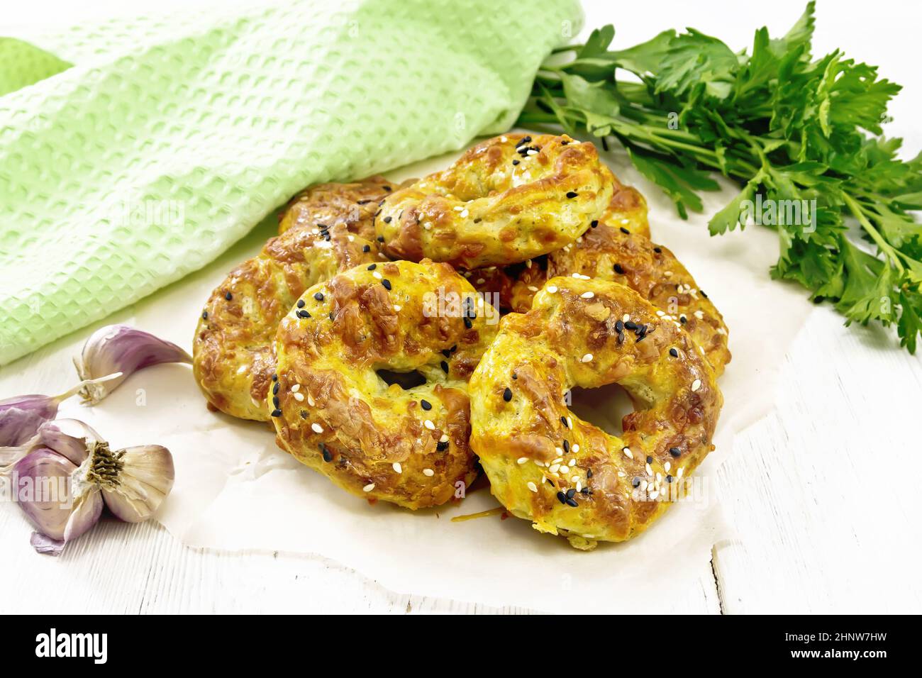 Bagels di cagliata e formaggio con aglio ed erbe su carta sullo sfondo di un asse di legno Foto Stock