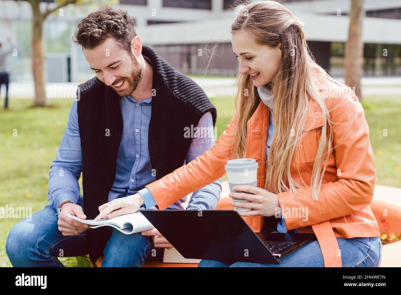 Compagni di studenti che guardano a un libro sul campus universitario che spiegano a vicenda i bit di conoscenza Foto Stock