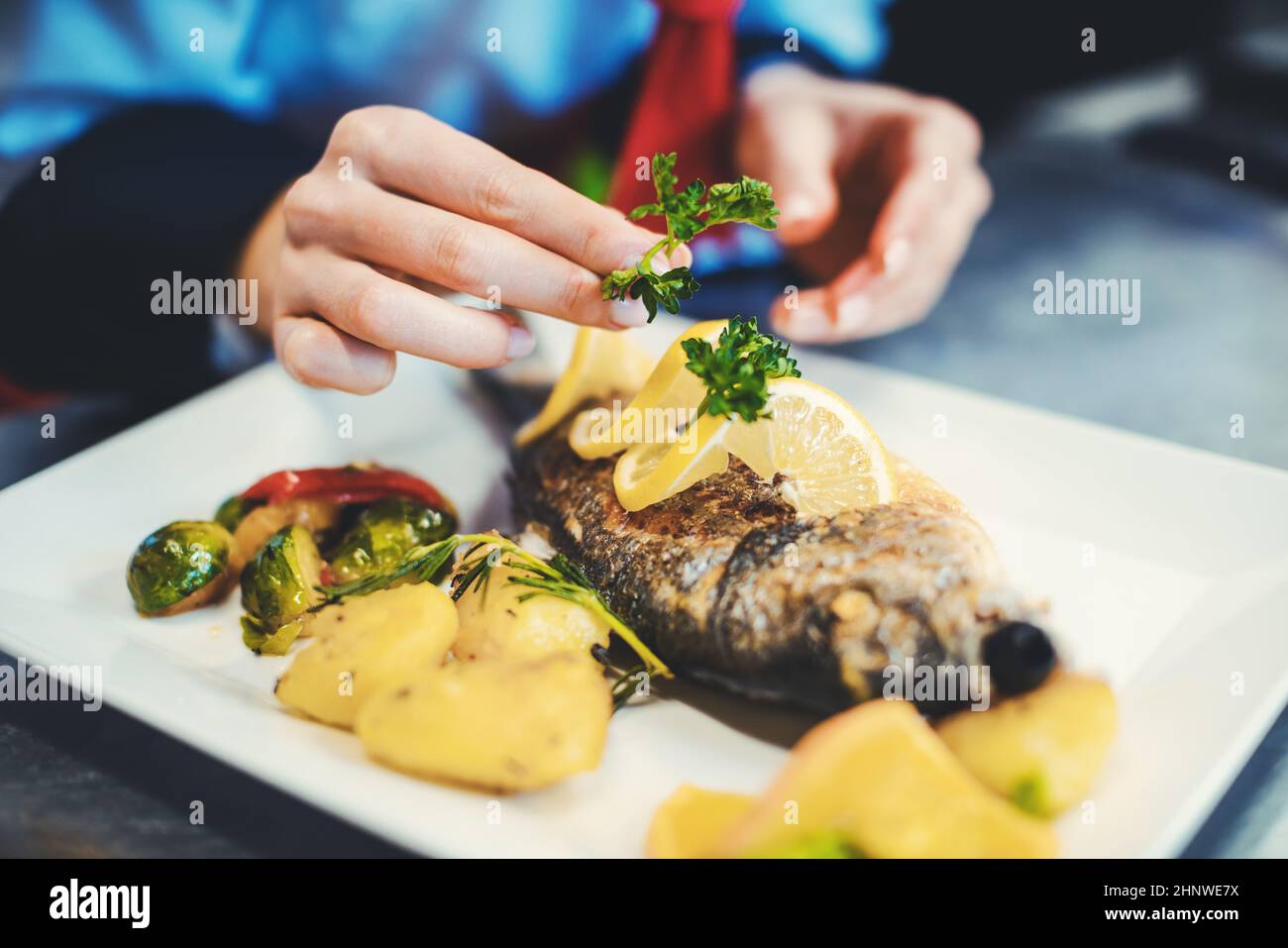 Cuoco chef in una cucina elegante ristorante rifinendo un piatto con cura e diligenza Foto Stock