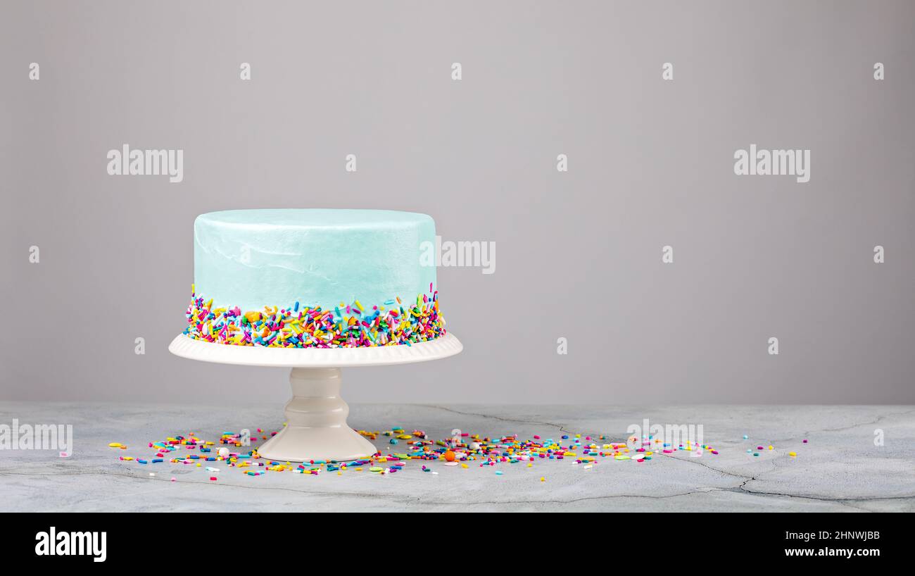 Torta blu con coloratissimi spruzzi su un supporto bianco Foto Stock