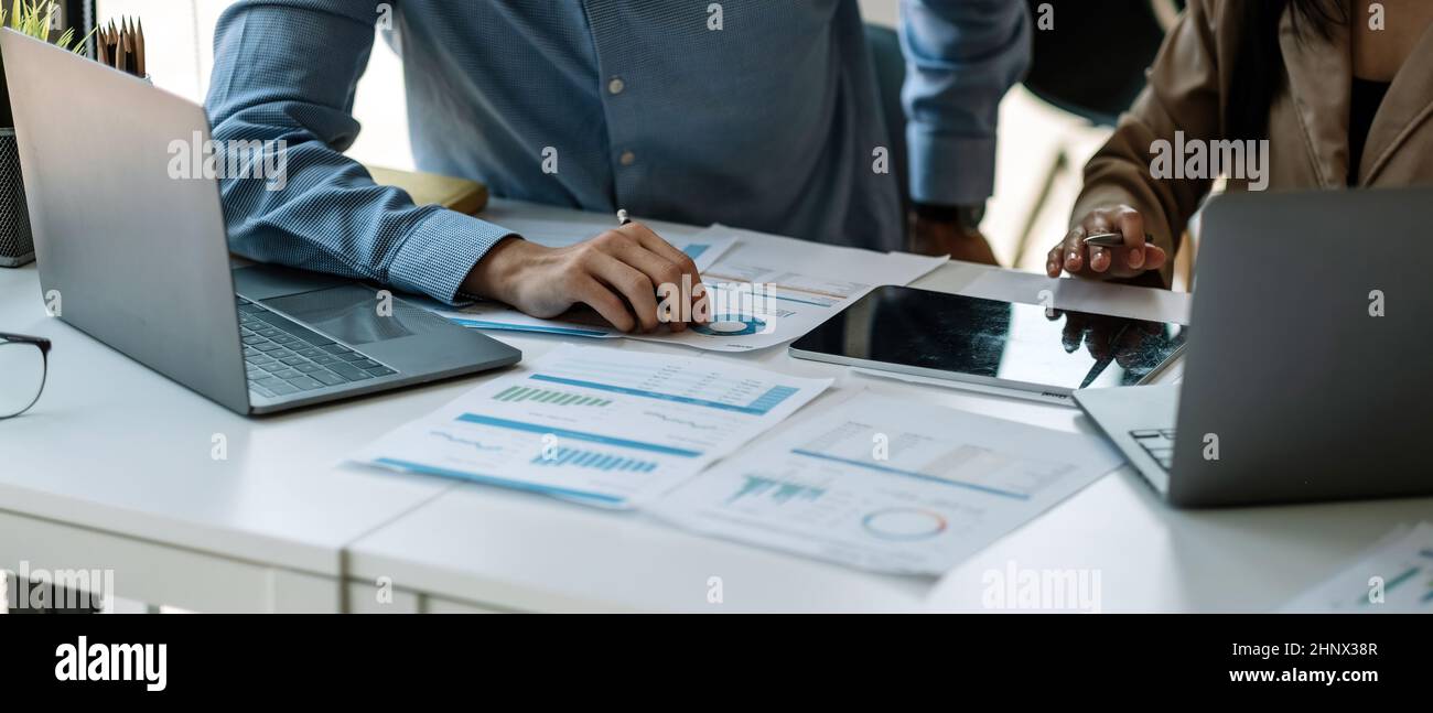 uomo d'affari e partnership indicando il grafico per analizzare il piano di marketing con calcolatrice e computer portatile su legno scrivania in ufficio Foto Stock