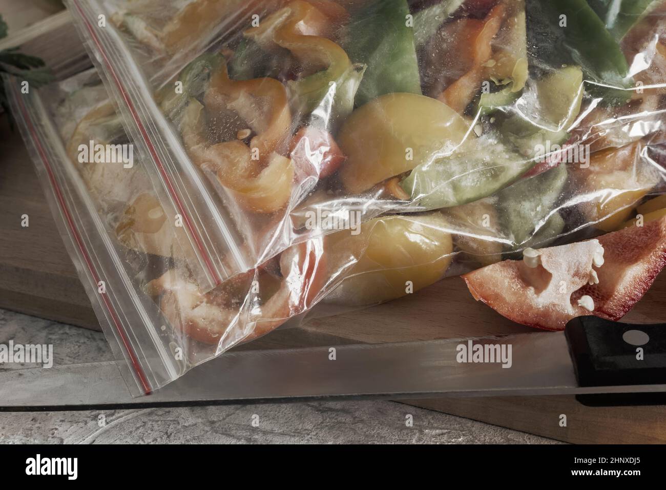 Affettato frutti maturi di peperone in sacchetti di cellophane, preparati per il congelamento e la conservazione a lungo termine nel comparto freezer del frigorifero. V. Anteriore Foto Stock