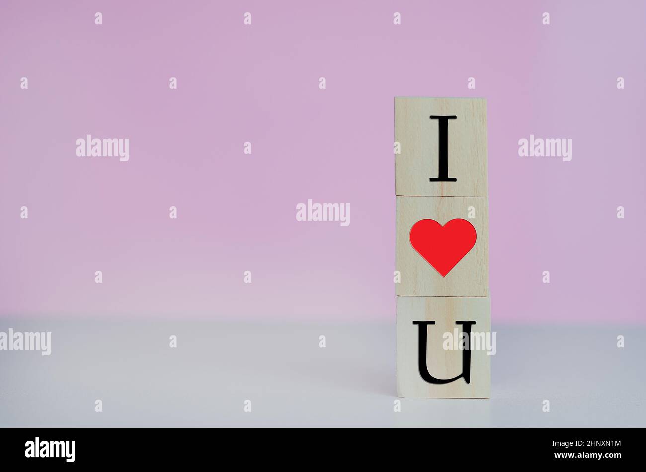 Cubi di legno con i amore u simbolo cuore sullo sfondo rosa e spazio copia. Foto Stock