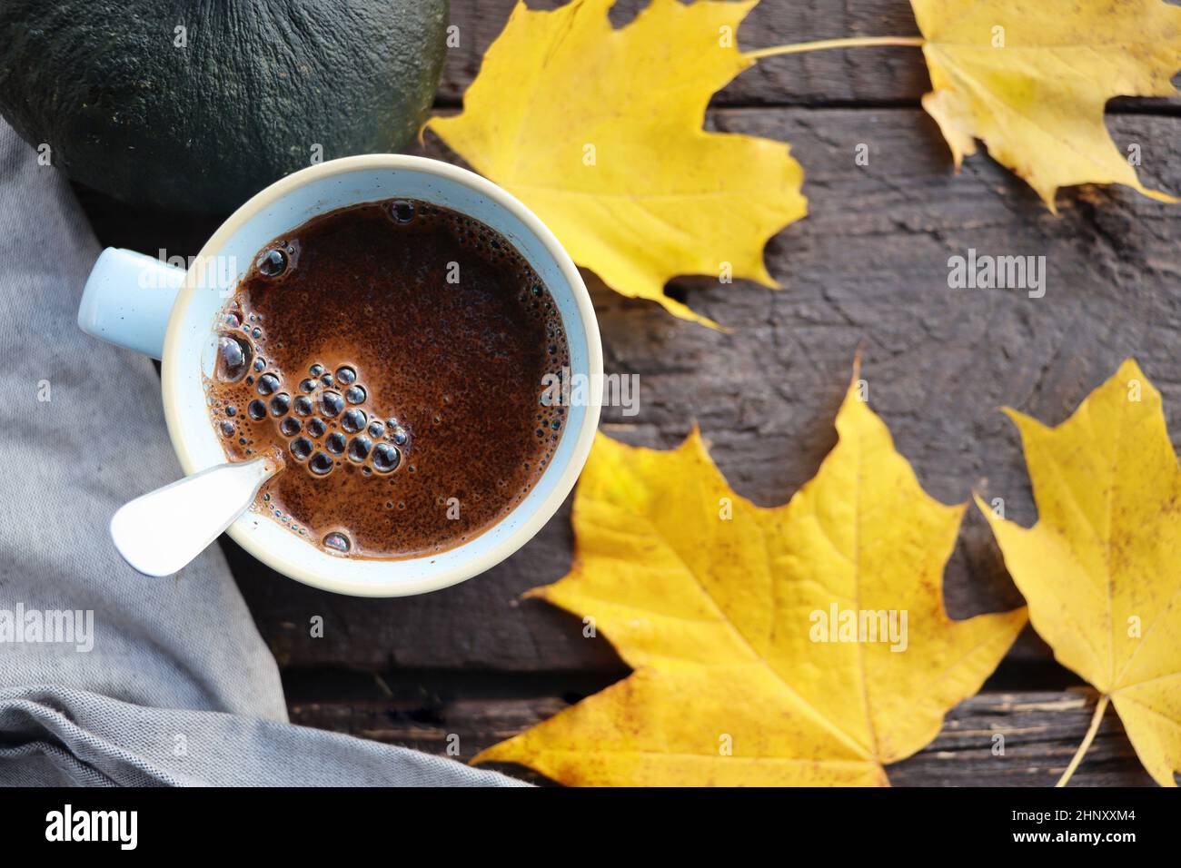 Sfondo autunno. Foglie d'autunno sfocate e fondo di zucca con una tazza di caffè calda. Foto Stock