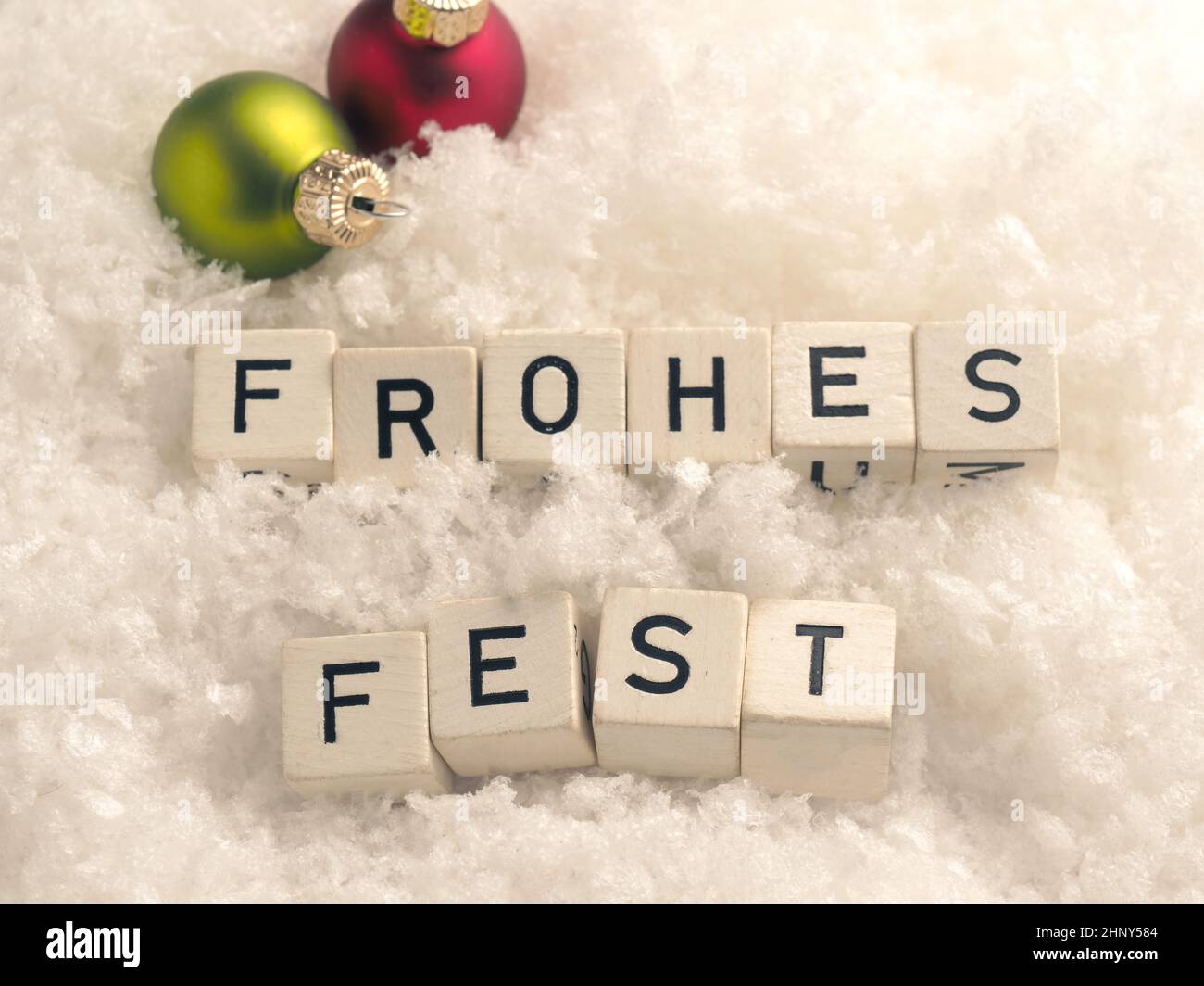 Frohes Fest, Natale allegro tedesco, blocchi di legno con colorati baubles di Natale nella neve Foto Stock