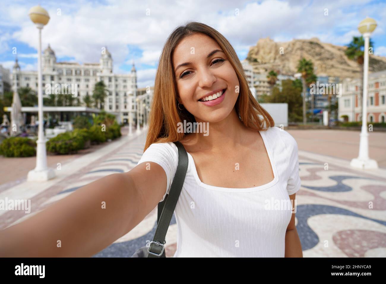 Selfie ragazza ad Alicante, Spagna. Autoritratto di giovane donna con Casa Carbonell e Monte Benacantil con il castello di Santa Barbara sullo sfondo. Foto Stock