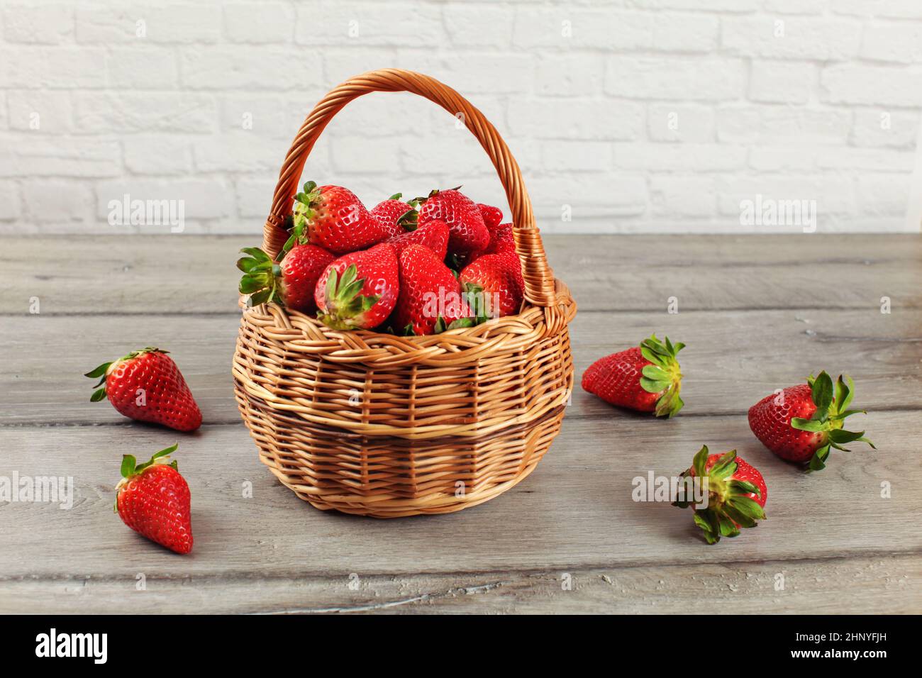 Cesto di Fragole, alcuni di loro versato sul legno grigio desk. Foto Stock