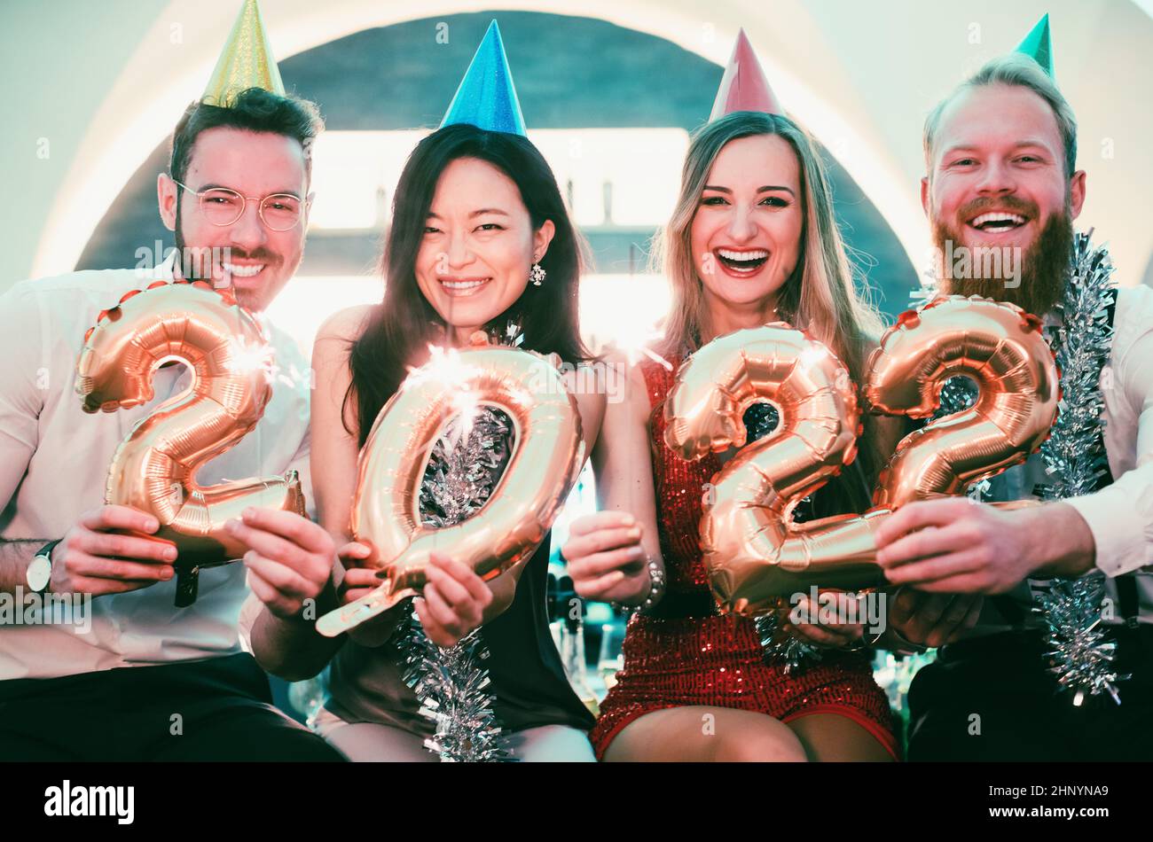 Uomini e donne che festeggiano il nuovo anno 2022 con scintille e vino Foto Stock