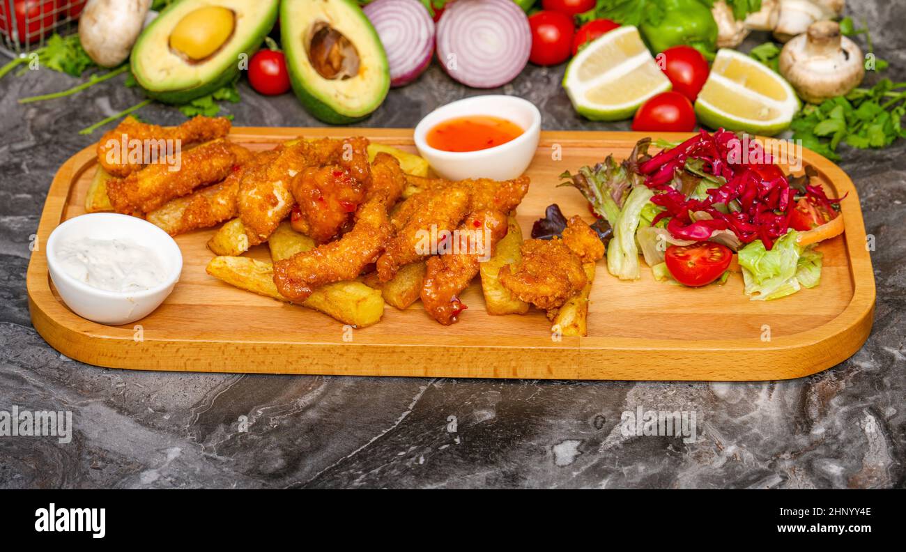Pezzi di pollo fritto e patinato croccante con patatine fritte e insalata Foto Stock