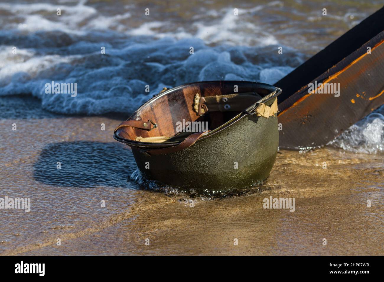 Wet Amcerian WW2 M1 casco lasciato dietro sulla spiaggia. Giorno dell'evento di rievocazione del D-Day. Hel, Polonia Foto Stock
