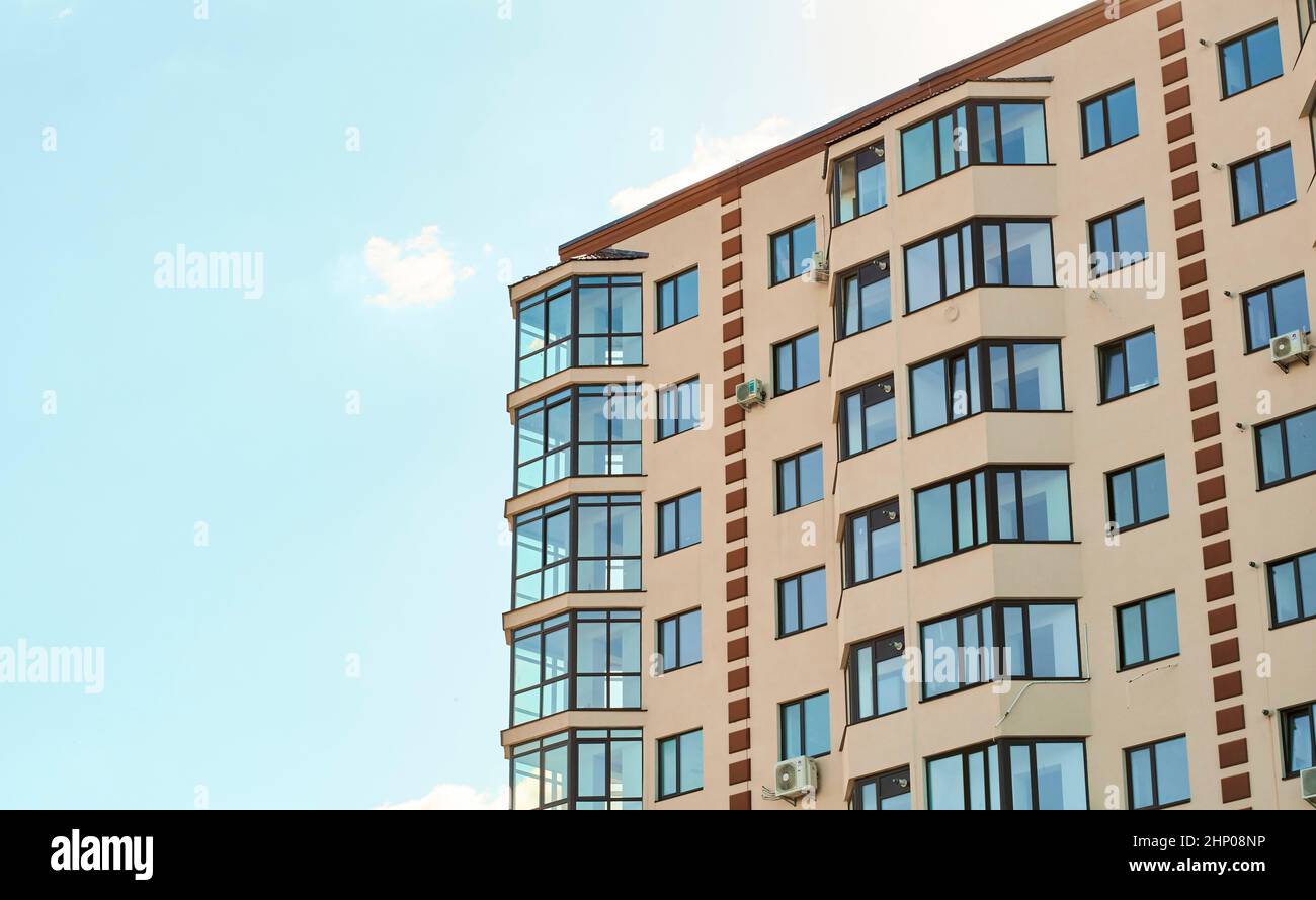 Nuovo tipo condominio residenziale. Vista della moderna facciata in stucco di sabbia con grande balcone con finestra a golfo e finestre in vetro massiccio. Blocco di f Foto Stock