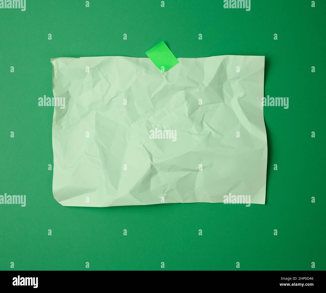 foglio di carta verde bianco, rettangolare, sgualcito, incollato con carta verde appiccicosa su sfondo verde Foto Stock