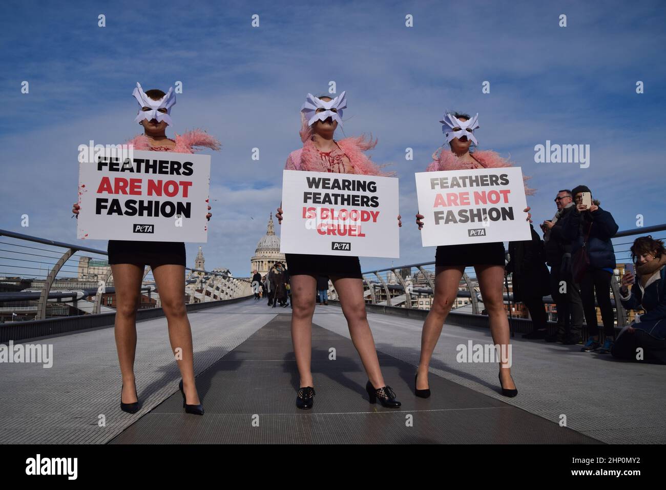 Londra, Regno Unito. 17th febbraio 2022. Gli attivisti DI PETA che indossano maschere per uccelli e con gilet 'sanguinose e scottate' esposte hanno organizzato una 'passerella' sul Millennium Bridge per protestare contro l'uso di piume di uccello in abiti e accessori alla London Fashion Week. Foto Stock