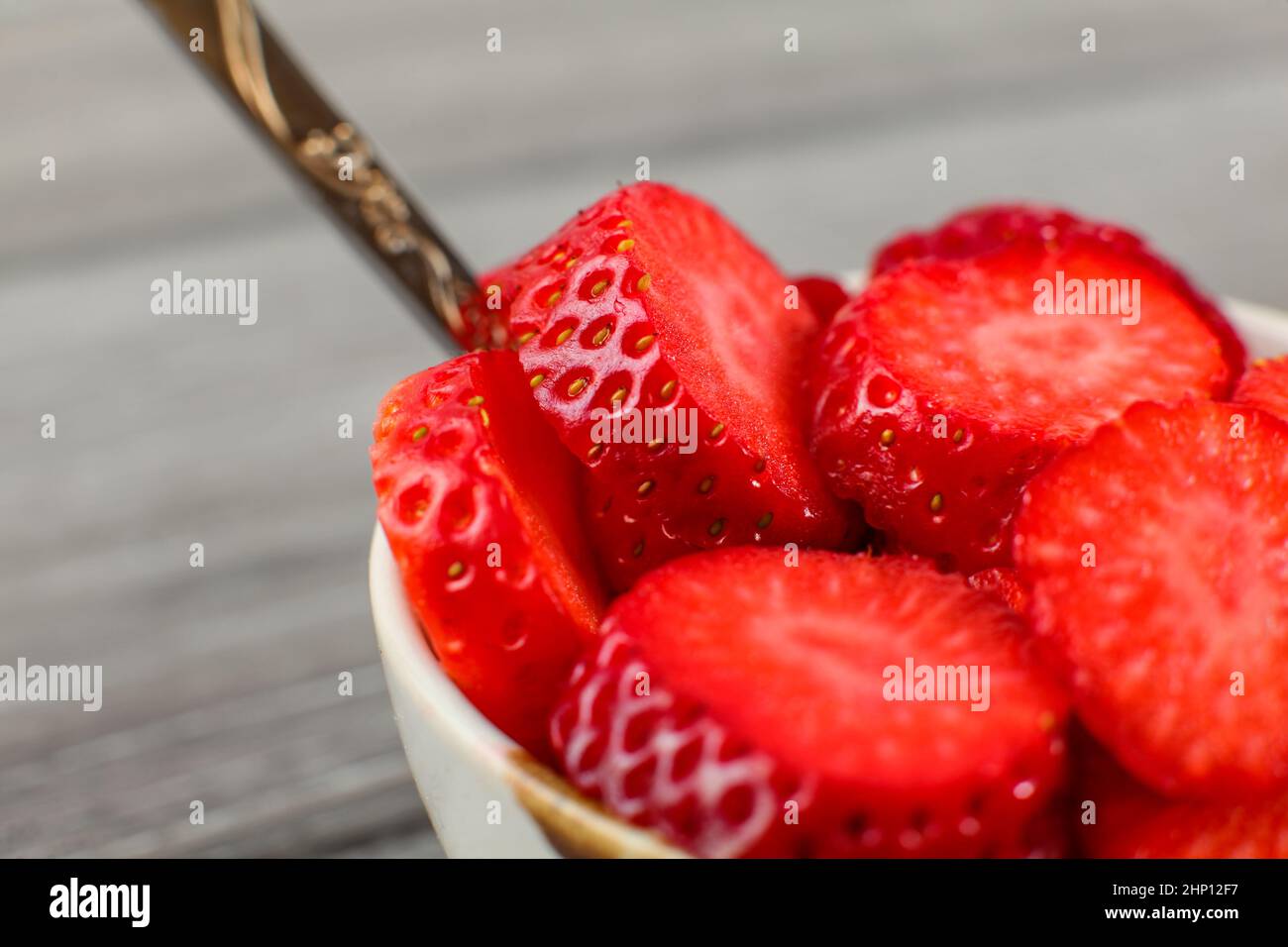 Close up - piccola ciotola con cucchiaio pieno di fragole tagliate a piccoli pezzi di cerchio. Pronto a mangiare snack sani. Foto Stock