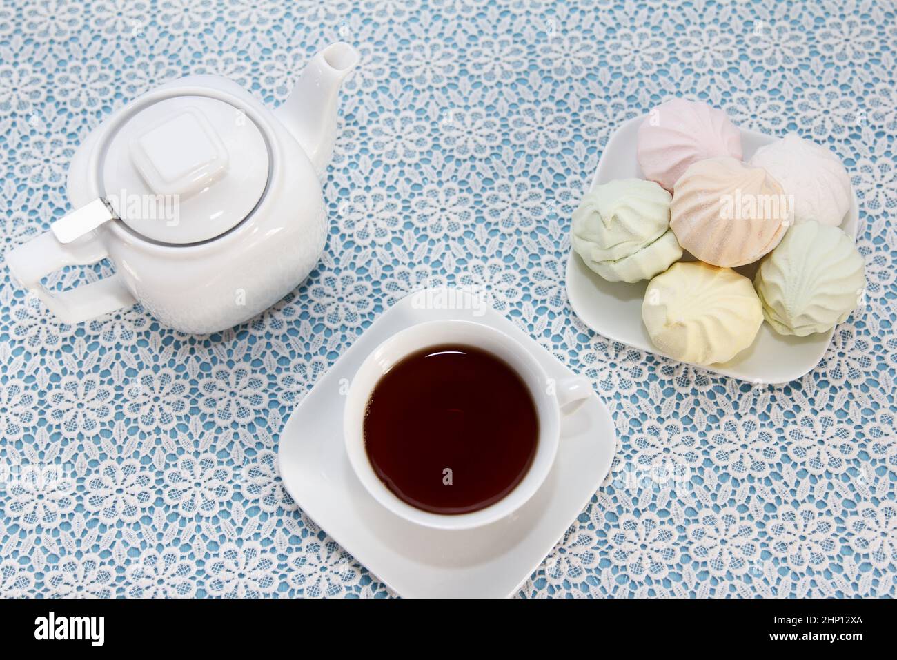 Tradizionale e delizioso tè preparato in una tazza, teiera e marshmallows d'aria si trovano sul tavolo, un dolce dessert Foto Stock
