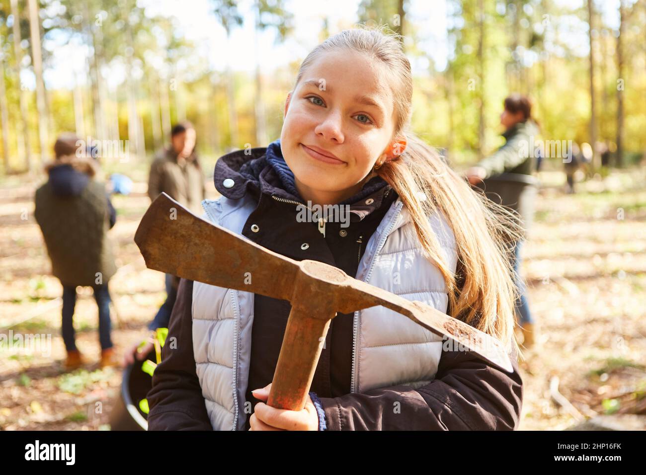 Ragazza con ascia adze nella foresta aiuta la sua famiglia nella campagna di rimboschimento sostenibile Foto Stock