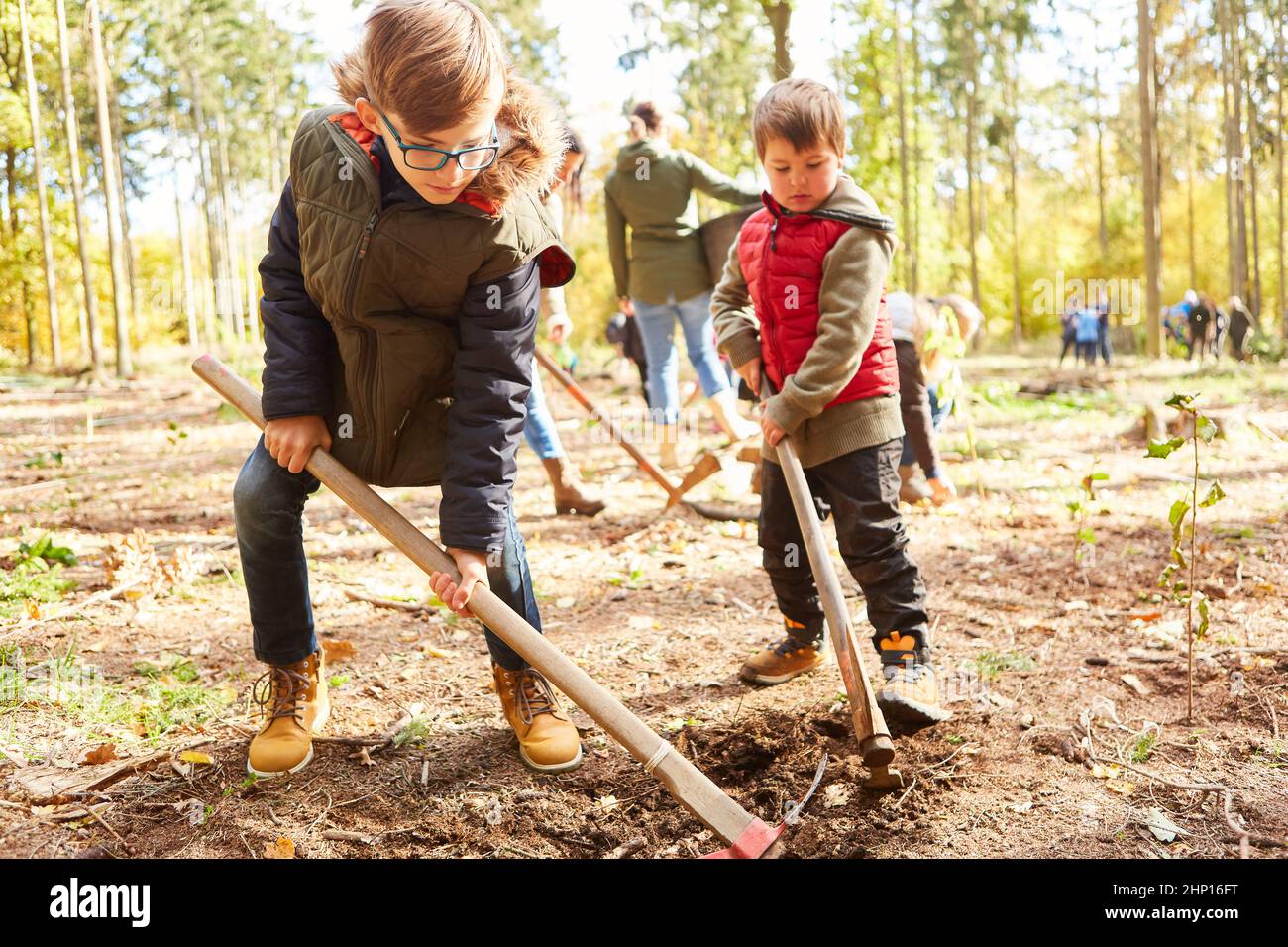 Due bambini piantano gli alberi insieme nella foresta durante un tour della foresta come campagna di conservazione della natura Foto Stock