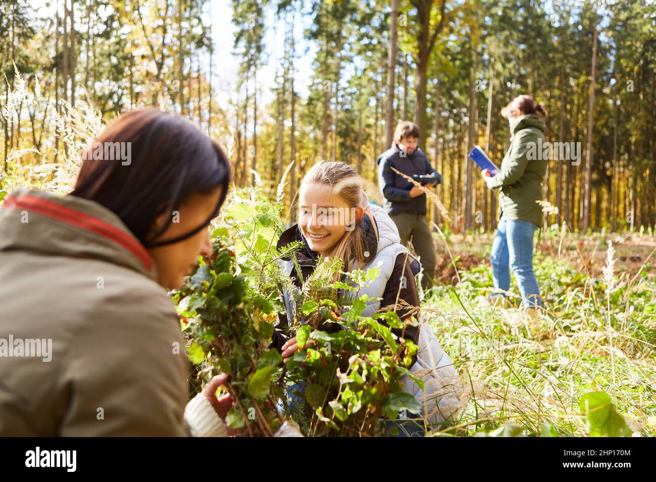 Madre e figlia aiutano i forestatori piantano alberi nella foresta per un rimboschimento sostenibile Foto Stock