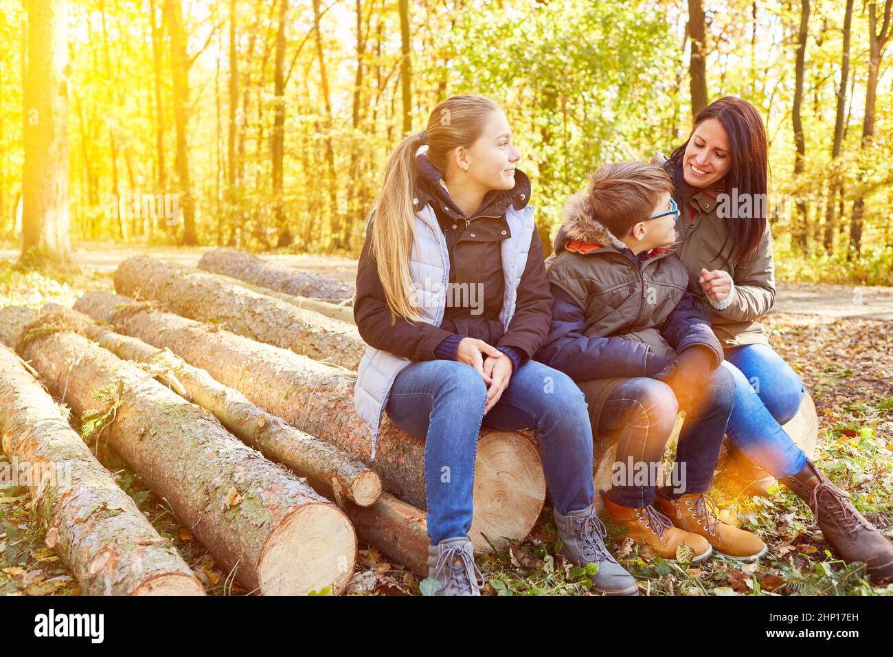 Famiglia con madre e due bambini si siede nella foresta su tronchi sgranati in estate Foto Stock