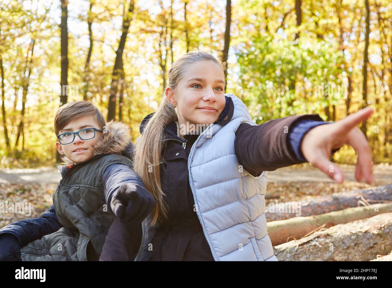 Fratello e sorella mostrano la direzione con la mano su un'escursione nella foresta in natura Foto Stock