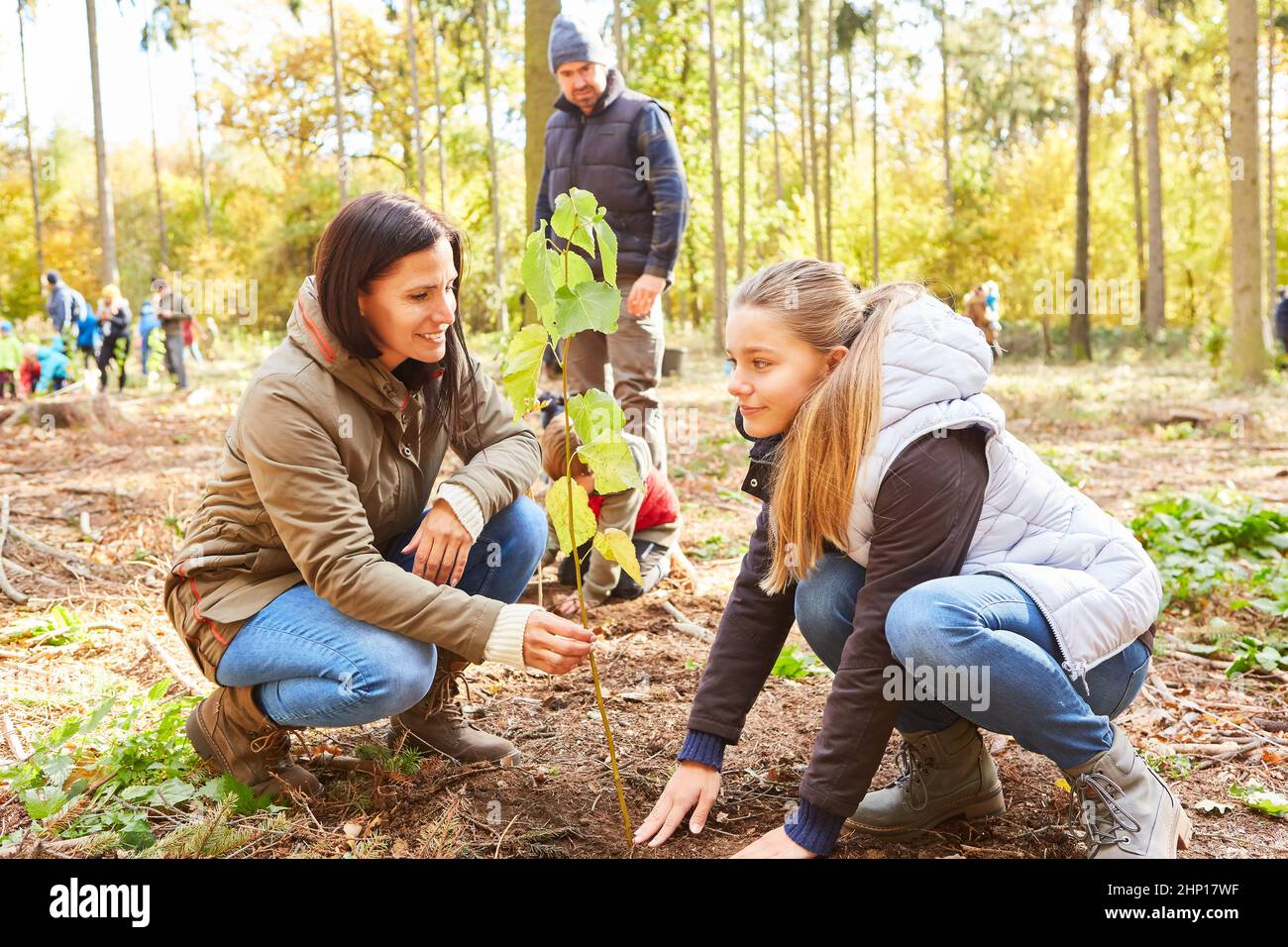 Madre e bambino come aiutanti volontari piantando albero in foresta per la protezione ambientale ed ecologia Foto Stock