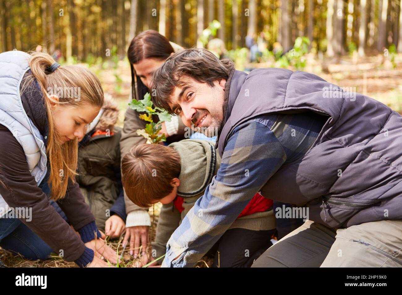 Forester e famiglia piantano un albero insieme nella foresta per il rimboschimento ecologico Foto Stock