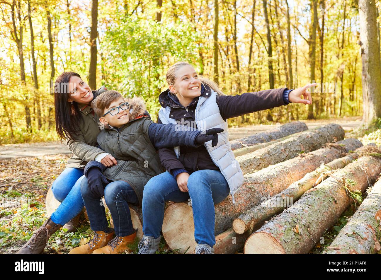 Madre e due bambini si siedono sul log e si divertono durante il viaggio nella natura nella foresta Foto Stock