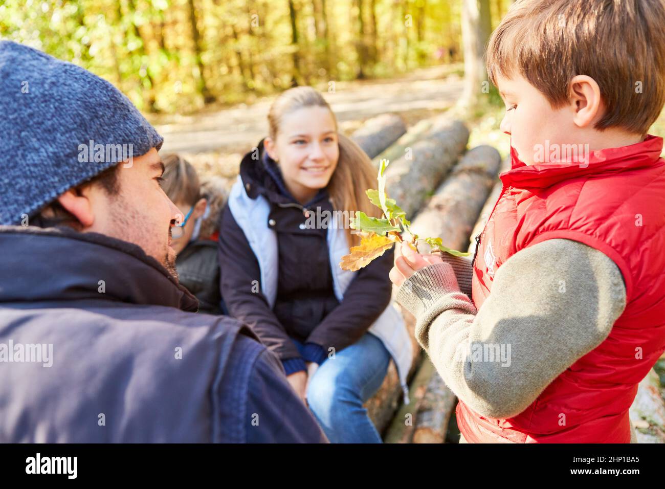 I bambini dal centro di day-care con un forester distrettuale alla ricerca dell'albero come formazione della foresta nel giorno della scuola della foresta Foto Stock