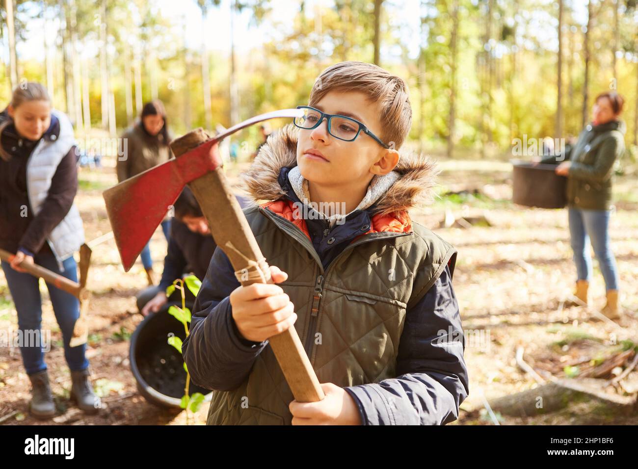 Il ragazzo tiene un'ascia adze durante una rimboschimento nella foresta durante una campagna volontaria di conservazione della natura Foto Stock
