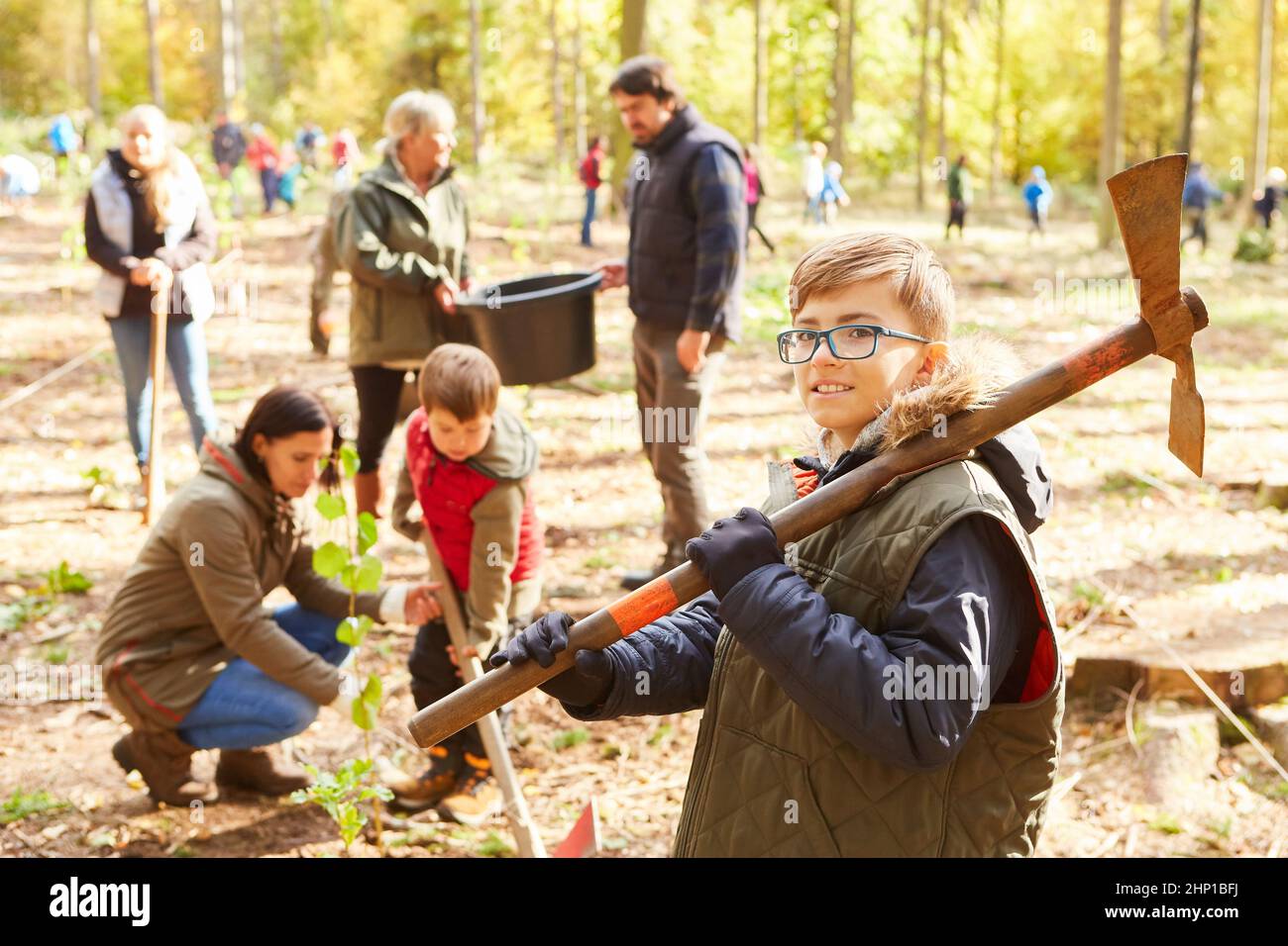 Gruppo di volontari e bambini che piantano alberi nella foresta per la sostenibilità e la protezione del clima Foto Stock