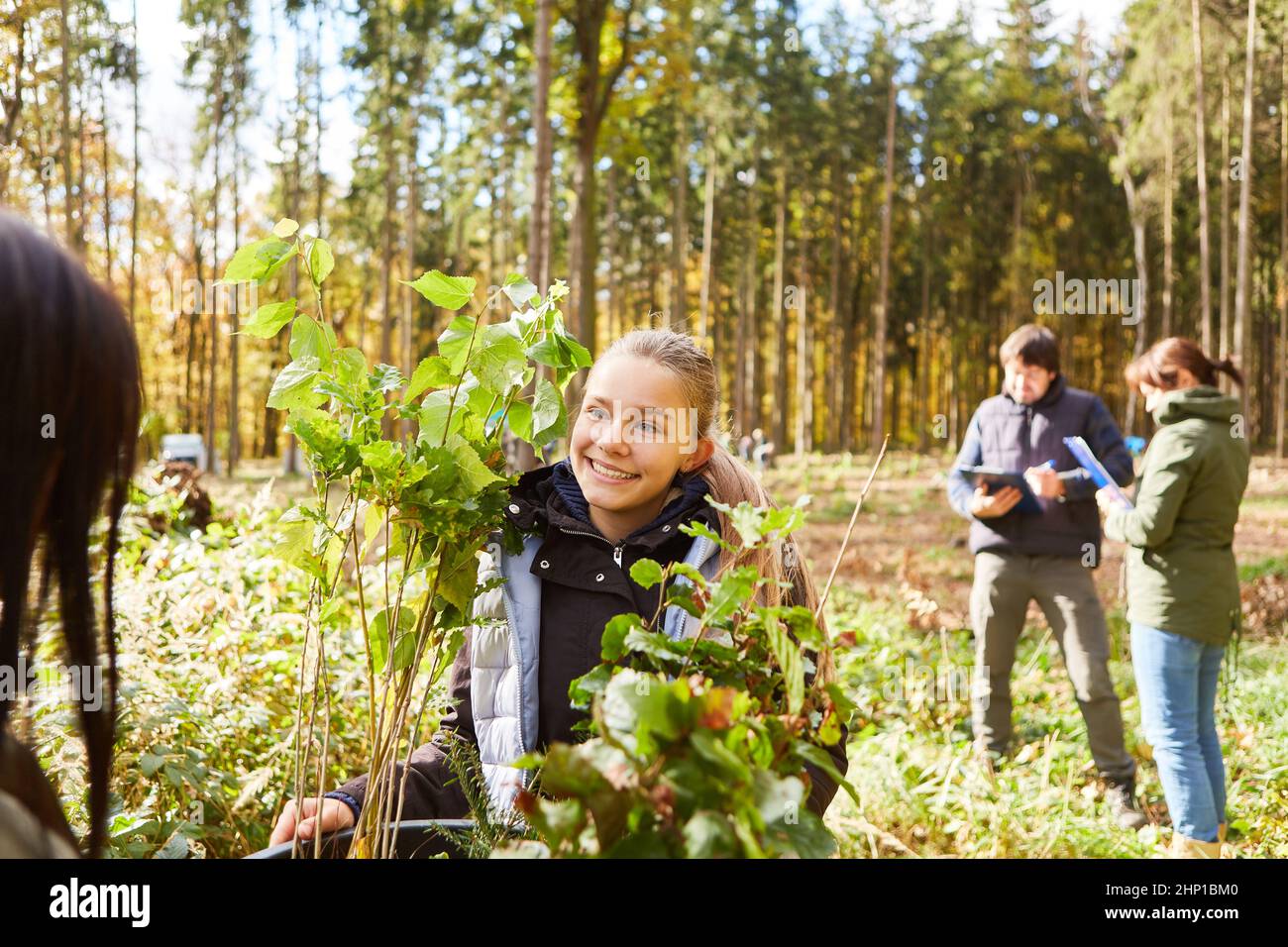 Girl aiuta a piantare un albero nella foresta in una campagna di rimboschimento per una maggiore sostenibilità Foto Stock