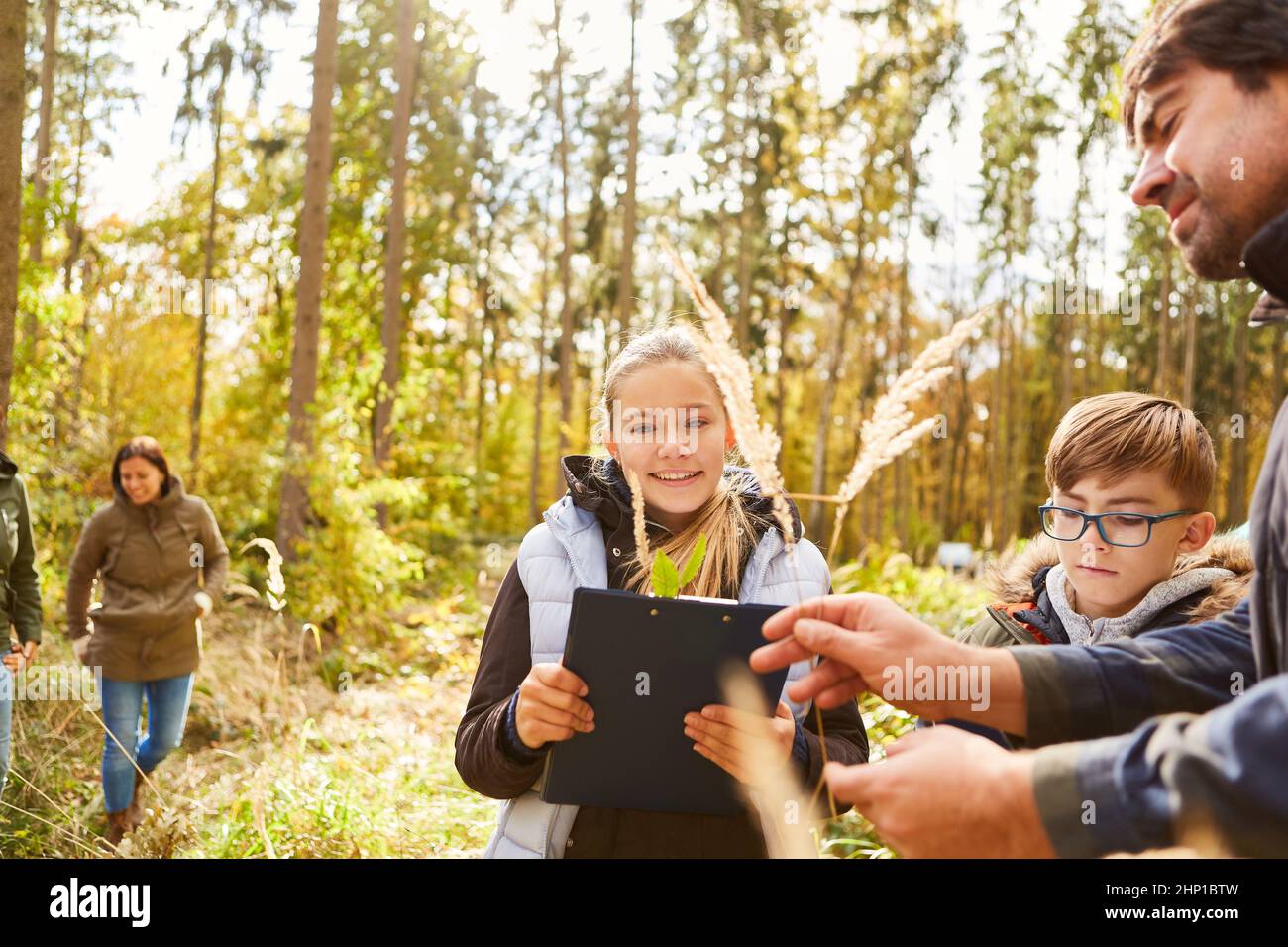 Bambini e forestatori durante le lezioni di botanica e storia naturale nella foresta in una giornata di scuola forestale Foto Stock