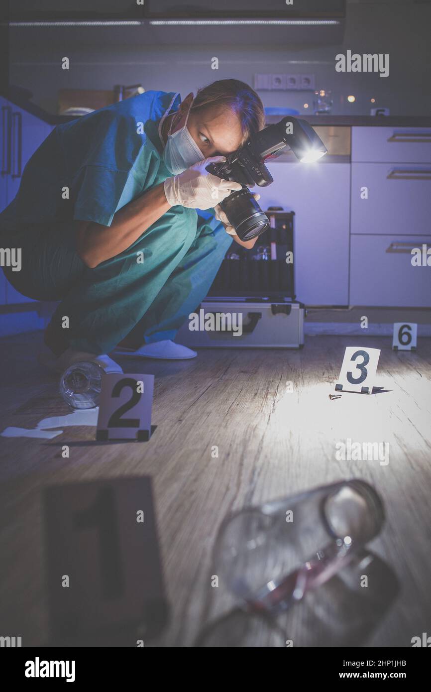 Specialista forense in tuta protettiva per scattare delle foto su una scena del crimine Foto Stock