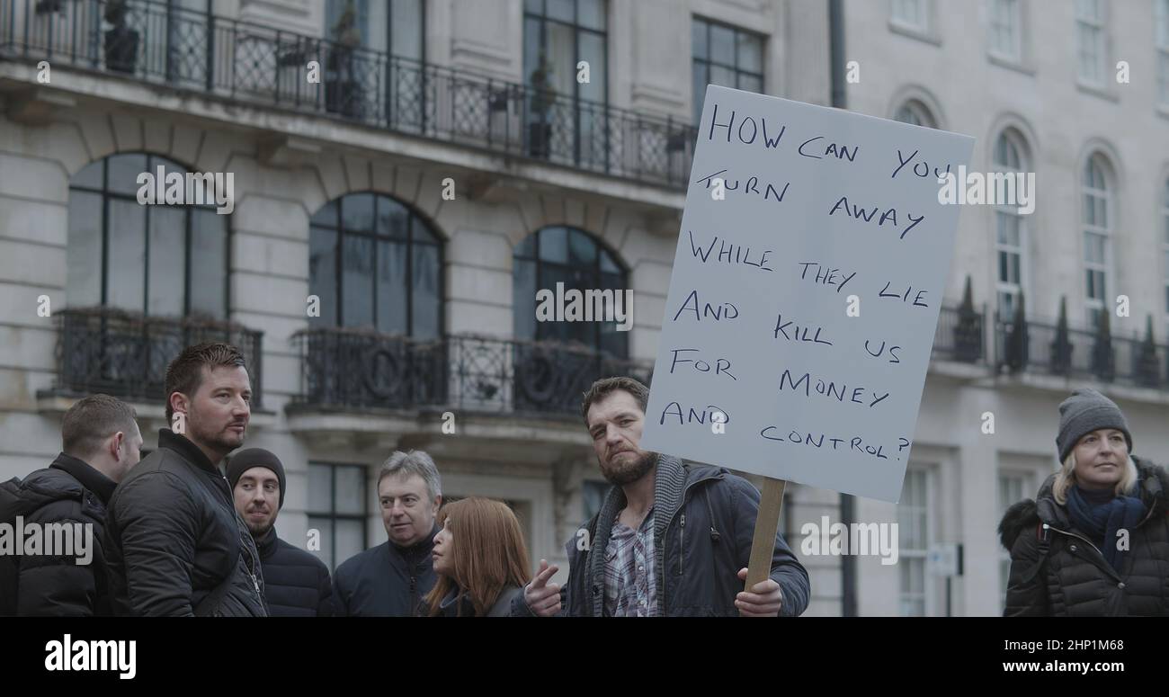 Londra, UK - 01 22 2022: Uomo protesta a Portland Place tenendo un cartello, “come si può girare via mentre si mentono e ci uccidano per denaro e controllo”. Foto Stock