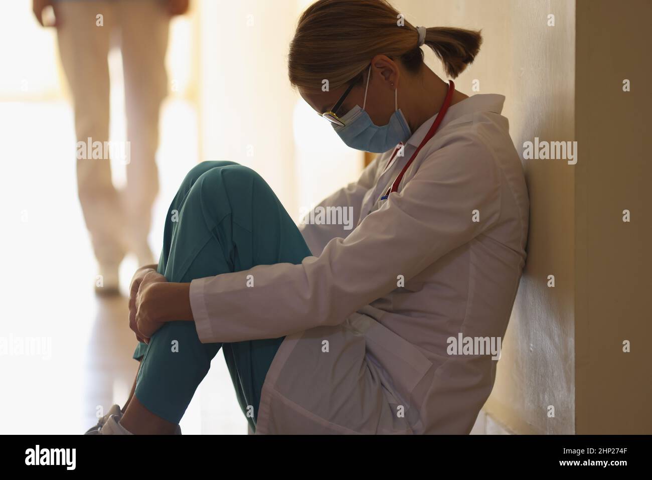 Una dottoressa è seduta sul pavimento nel corridoio, primo piano Foto Stock