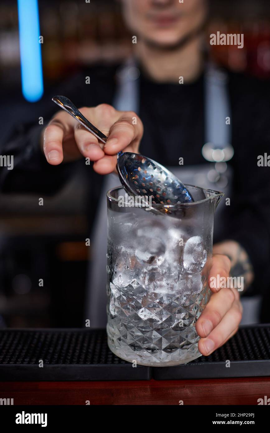 Il barista professionista crea un cocktail alcolico con ghiaccio utilizzando un filtro. Primo piano Foto Stock