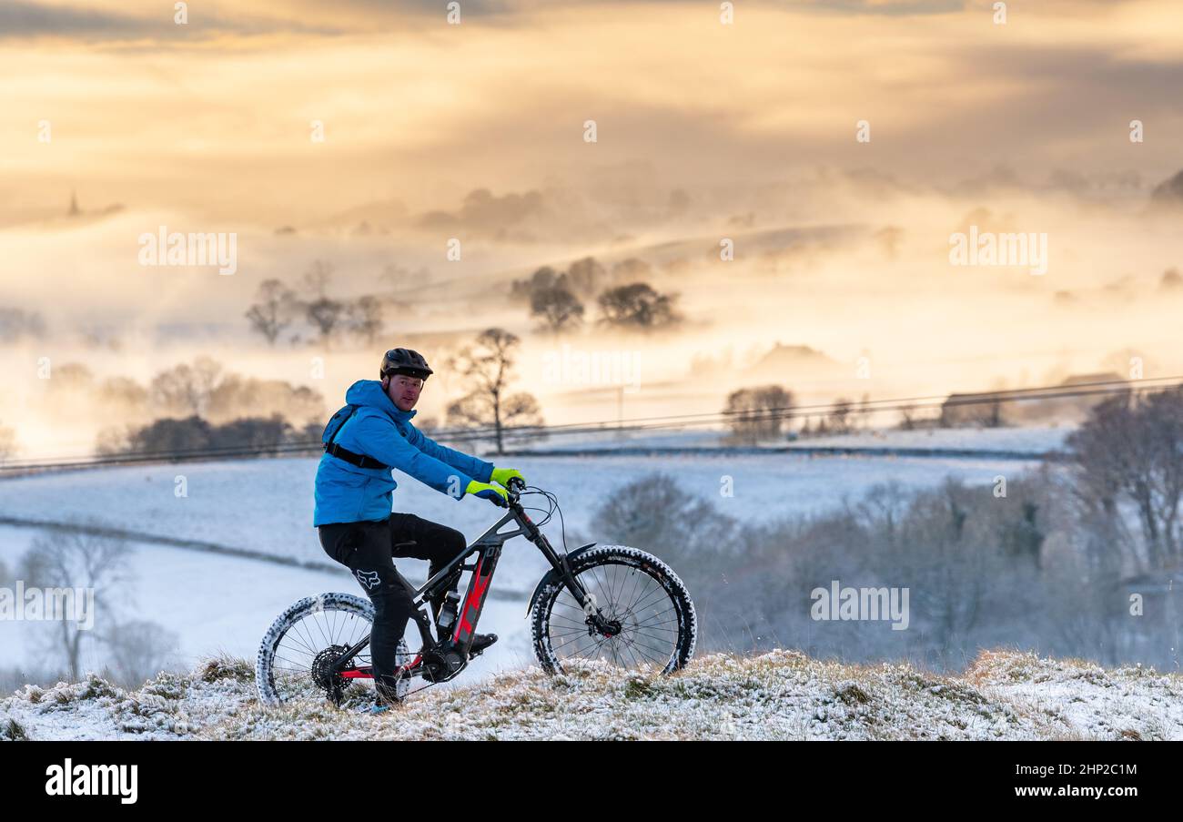 Mountain biker sulle pendici inferiori di Ingleborough, che si affaccia su un'inversione di nuvole nella valle inferiore. North Yorkshire, Regno Unito. Foto Stock