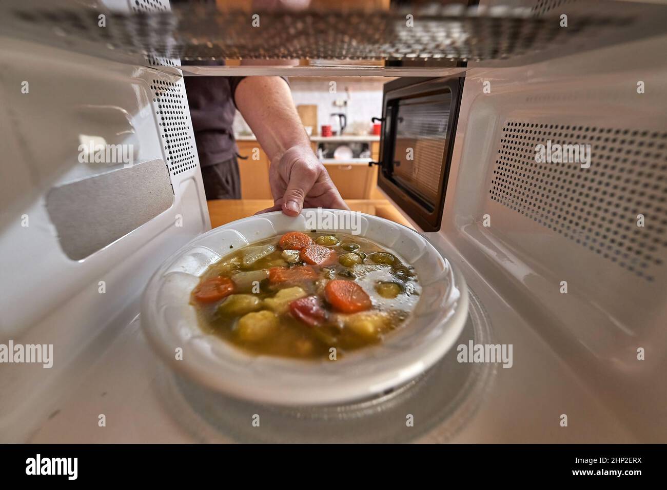 Riscaldare il cibo in un forno a microonde visto dall'interno del retro, un piatto di zuppa di verdure Foto Stock