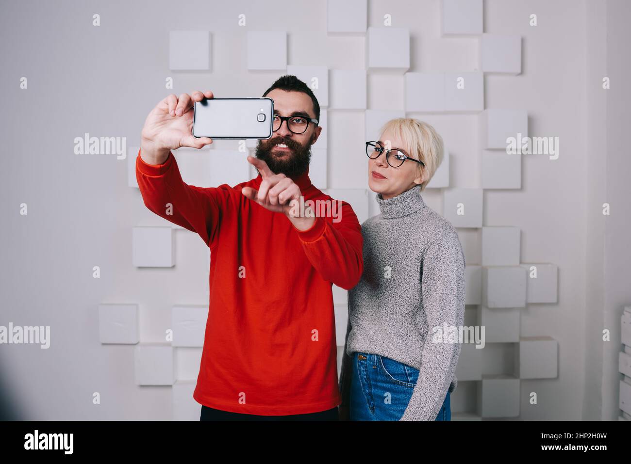 Coppia soddisfatta che si prepara a prendere selfie in studio Foto Stock