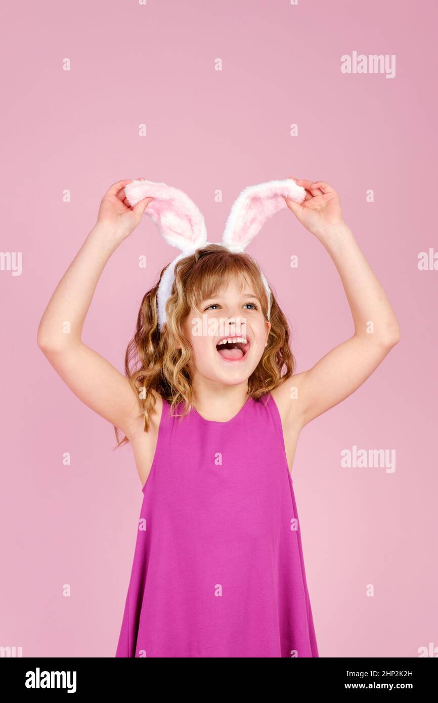 Piccola ragazza caucasica che tocca il bunny orecchi fascia Foto Stock