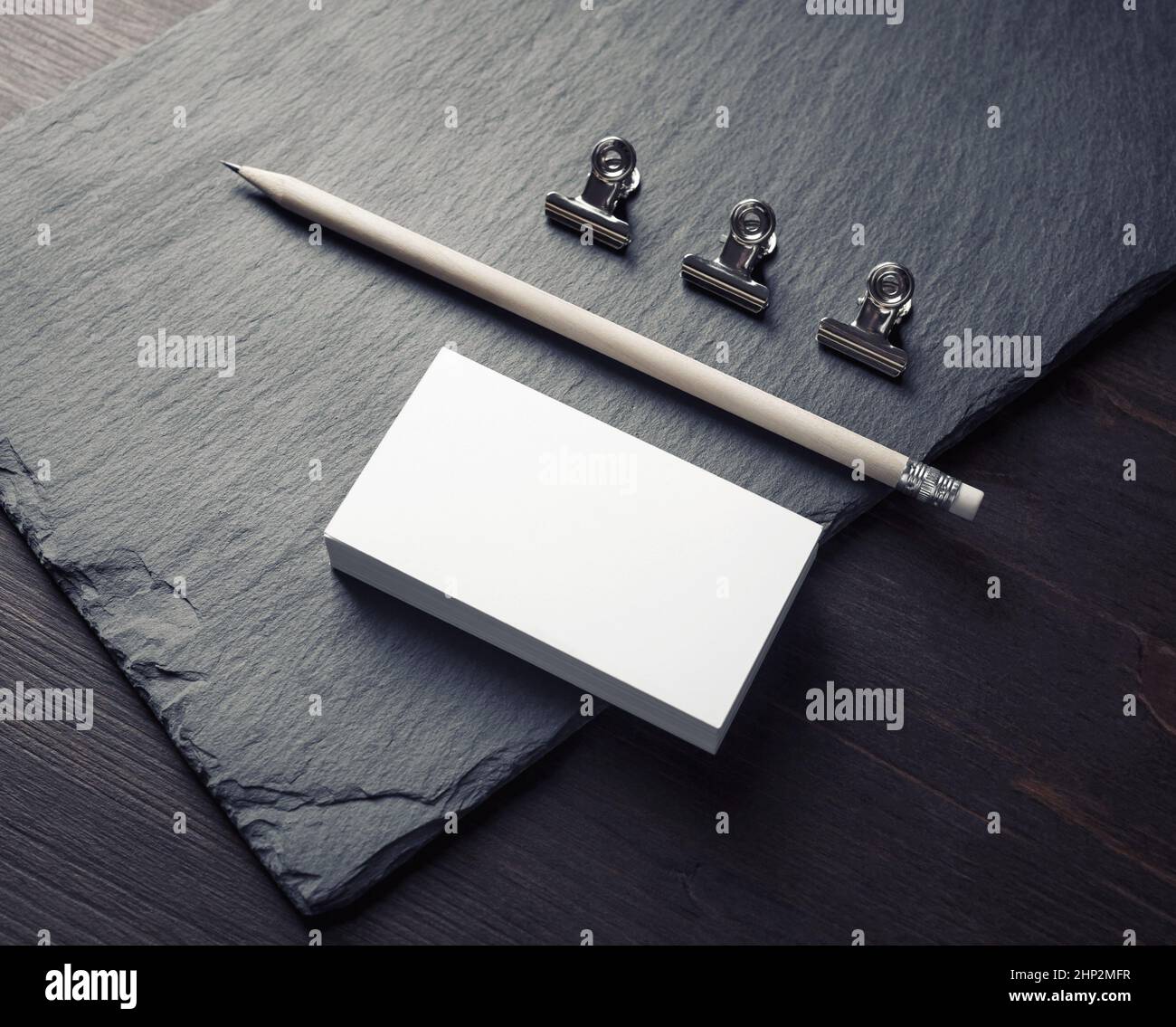 Foto di biglietti da visita bianchi, matita e clip. Mockup per ID. Foto Stock