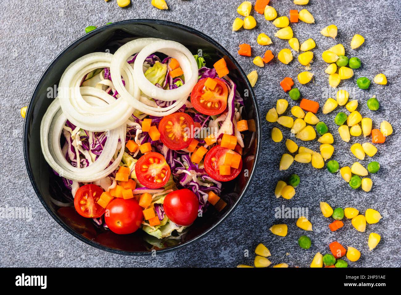 Vista dall'alto della ciotola per insalata colorata e sana con pomodori foglie fresche miste di verdure in un piatto su sfondo di pietra di cemento, salad snack Foto Stock