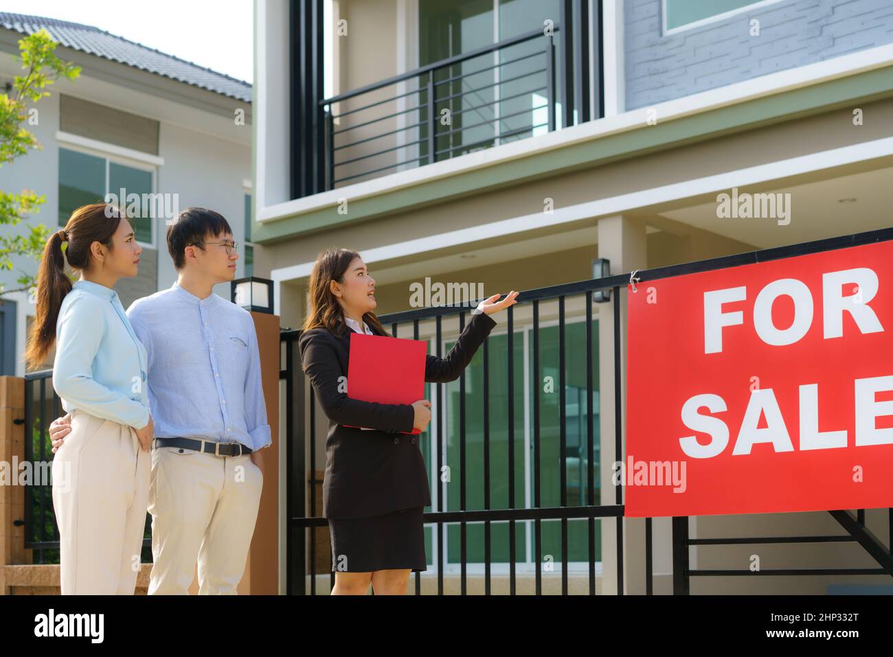 Donna asiatica Agente broker immobiliare che mostra un dettaglio della casa nel suo file per la giovane coppia asiatica amante cercando e interesse a comprarlo. Acquisto di una nuova ora Foto Stock