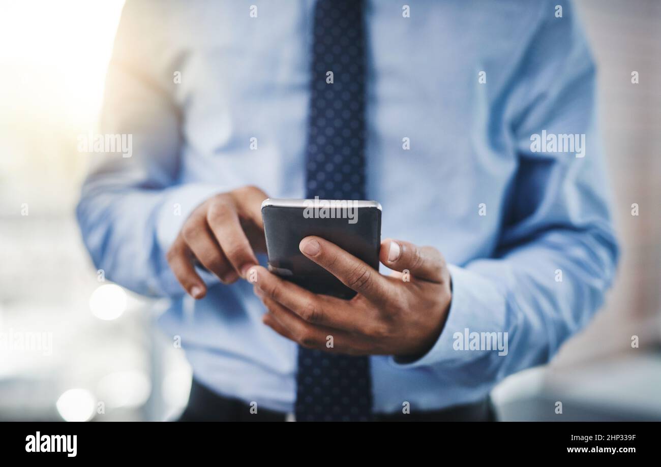 Il successo dipende dalle mosse che fate. Scatto corto di un uomo d'affari irriconoscibile usando il suo telefono in ufficio. Foto Stock